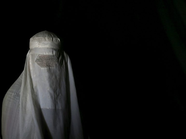 An Afghan refugee woman, clad in a burqa and returning from Pakistan, watches a short video clip about mines at a mines and explosives awareness program at a United Nations High Commissioner for Refugees (UNHCR) registration centre in Kabul, Afghanistan, Sept. 2, 2015. Photo by Ahmad Masood/REUTERS