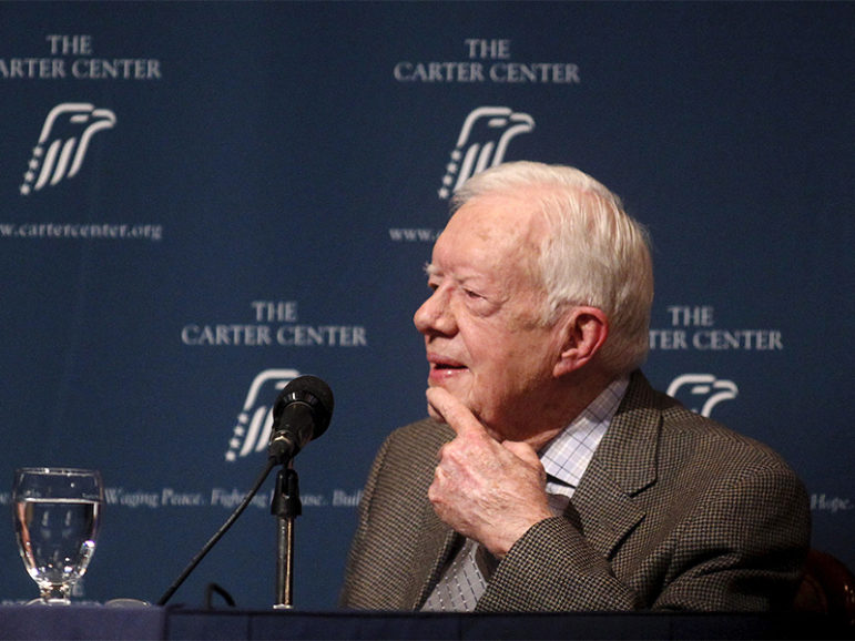 Former U.S. President Jimmy Carter listens as wife Rosalynn Carter (not pictured) speaks during 