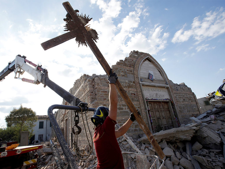 A firefighter carries away a crucifix from San Lorenzo e Flaviano church following an earthquake in San Lorenzo, in central Italy, on August 26, 2016. Photo courtesty of REUTERS/Max Rossi