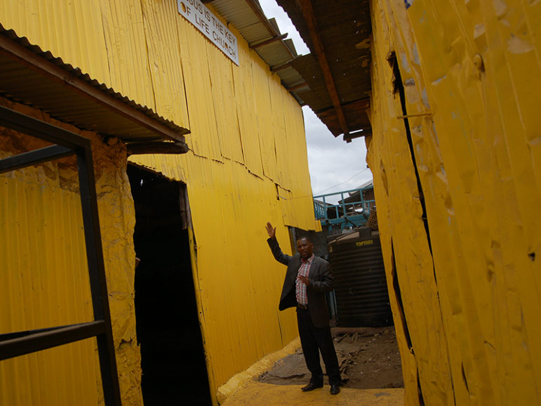 Pastor Steve Shirima, the leader of Jesus Is the Key of Life, a Pentecostal church, explains how his church was painted yellow. The church is deep within the shacks of a slum. RNS photo by Fredrick Nzwili