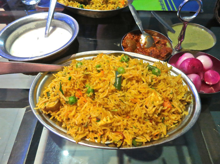 A dish of biryani served in New Delhi on Sept. 9, 2016, with, from left, a serving of raita and a selection of mixed pickles, mint sauce and pickled onions. RNS photo by Tom Heneghan