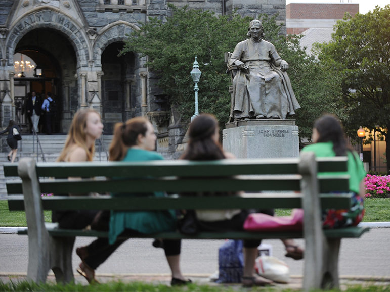 A statue of John Carroll, first archbishop of Baltimore and founder of Georgetown University, overlooks a group of women seated on a bench on the Georgetown campus in Washington on June 14, 2012.  Photo courtesy of REUTERS/Jonathan Ernst