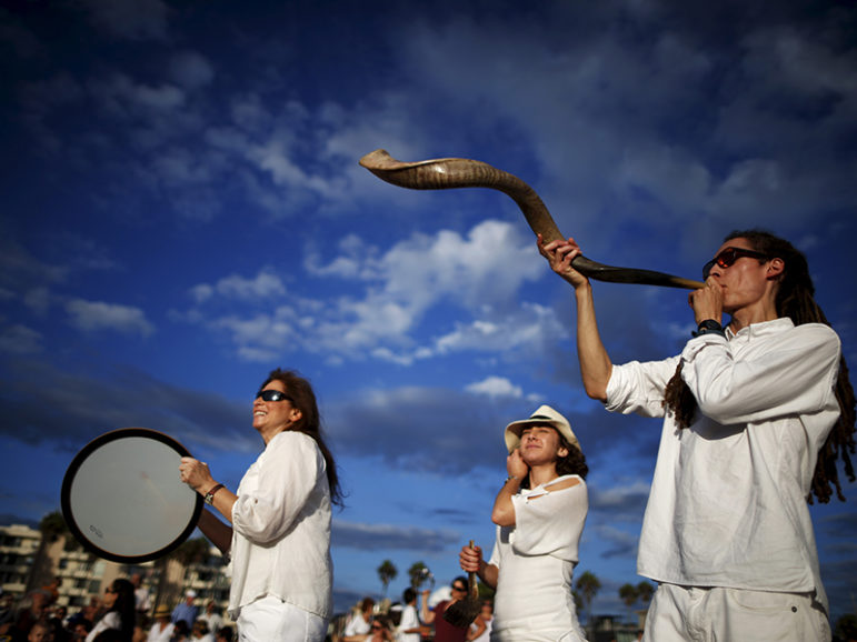 Jared Stein, right, blows a shofar as Rabbi Naomi Levy, left, plays a drum at the Nashuva Spiritual Community Jewish New Year celebration on Venice Beach in Los Angeles, Calif., on September 14, 2015. As Jews take part in the Tashlich prayer, a Rosh Hashanah ritual, bread crumbs are tossed into the waters to symbolically cast away sins. Photo courtesy of Reuters/Lucy Nicholson