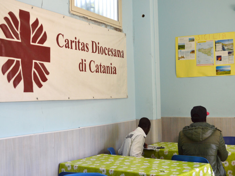Migrants sit at the Caritas center in Catania, Sicily. Religion News Service photo by Rosie Scammell