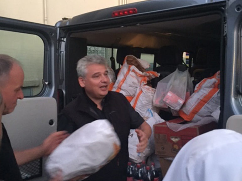 At 7 p.m. at least twice a week, Archbishop Konrad Krajewski pulls up in a large gray van and unloads heavy containers filled with steaming risotto, fresh fruit and drinks for the men, women and children who will soon bed down in the open alley for the night. RNS photo by Josephine McKenna