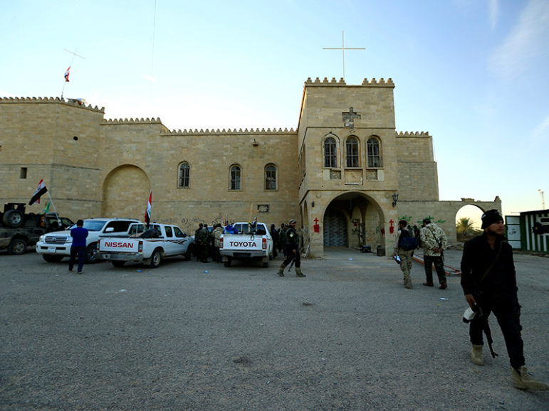 Fighters from the "Kataeb Babylon", a group of Christian fighters who fight alongside the Hashd Shabi, Shi'ite fighters, walk at the Mar Behnam monastery after the town was recaptured from the Islamic State, in Ali Rash, southeast of Mosul, Iraq on November 21, 2016. Photo courtesy of Reuters/Thaier Al-Sudani