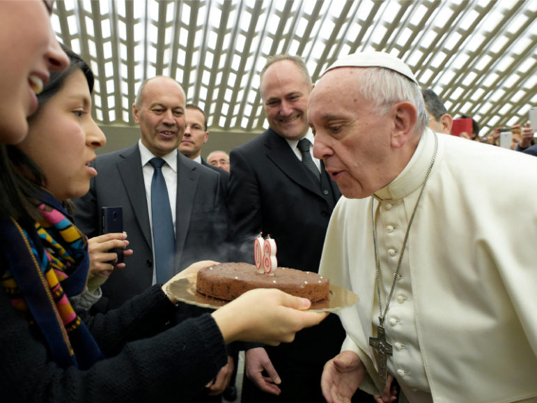 During his Wednesday general audience at the Vatican on Dec. 14, 2016, Pope Francis blows out candles on a birthday cake received from well-wishers to celebrate his 80th birthday on Saturday. Photo courtesy of  Osservatore Romano/Handout via Reuters. 