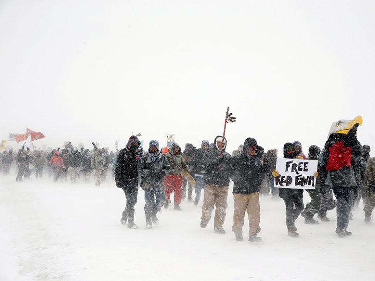 Veterans join activists in a march just outside the Oceti Sakowin camp during a snowfall as 