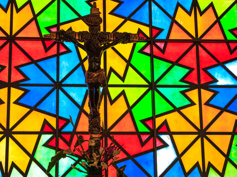 Stained glass behind a crucifix in a Catholic church.  Photo by Murray Foubister/Creative Commons