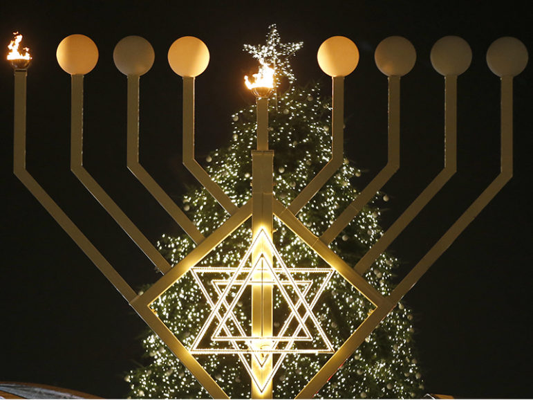 A giant menorah stands in front of a Christmas tree at the Brandenburg Gate to celebrate both winter holidays in Berlin on Dec. 16, 2014. Photo courtesy of Reuters/Fabrizio Bensch