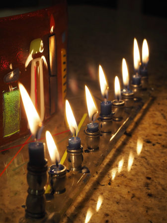 Low burning candles on a menorah. Photo courtesy of Andrew Leonard via Creative Commons