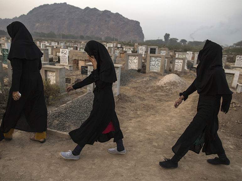 Ahmadi Muslim women walk past graves at the Ahmadi graveyard in the town of Rabwa, Pakistan, on Dec. 9, 2013. Three years earlier, 86 Ahmadi Muslims were killed in two simultaneous attacks on Friday prayers in Lahore. Photo by Zohra Bensemra/Reuters