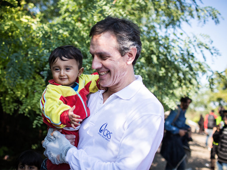 Sean Callahan, now president of Catholic Relief Services, holds 11-month-old Siad from Kobane,Syria, as he and his family cross the border from Serbia into Croatia, on Oct. 2, 2015. CRS and its partners are supplying food and other items to the refugees. Photo courtesy of Andrew McConnell via Catholic Relief Services