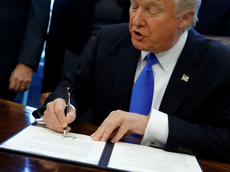 President Trump signs an executive order in the Oval Office at the White House in Washington, D.C. Photo courtesy of Reuters/Jonathan Ernst