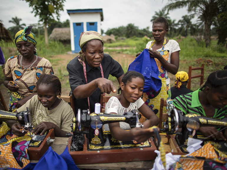 Sister Angélique Namaika, standing, in black, assists women with the clothes they are making at the Maison de La Femme in the town of Dungu, Orientale Province, Democratic Republic of Congo, on Aug. 1, 2013. Sewing is one of several income-generating skills that Sister Angélique teaches women to help them become more financially self-sufficient. Photo courtesy of the UN Refugee Agency/Brian Sokol