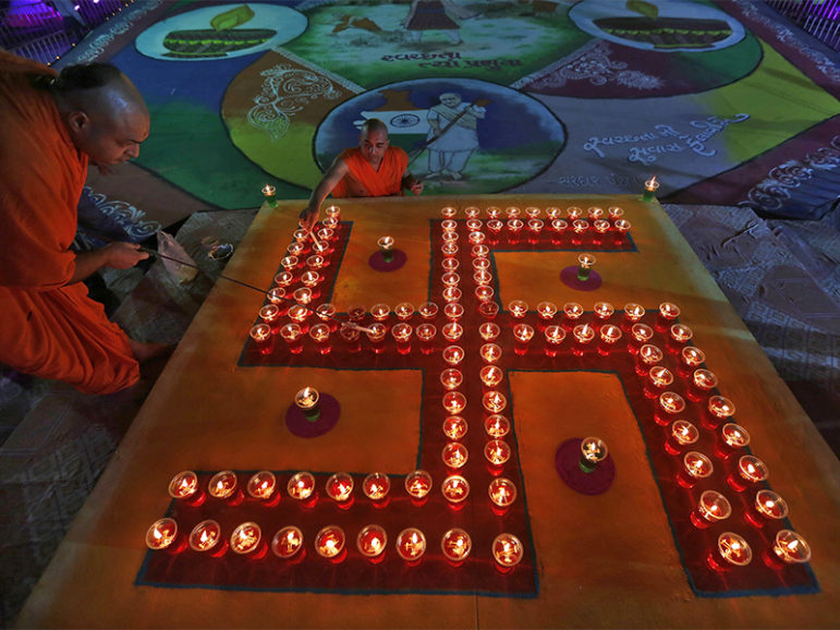 Hindu priests light oil lamps in a formation of the swastika, a Hindu symbol of peace, a day before the Hindu festival of Diwali in the western Indian city of Ahmedabad, on Oct. 22, 2014. Photo by Amit Dave/Reuters