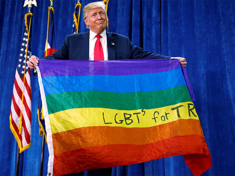 Republican presidential nominee Donald Trump holds up a rainbow flag with 