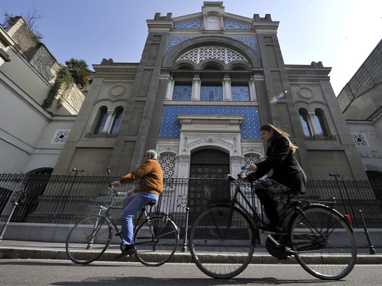 Two people ride bicycles past a synagogue in Milan, Italy, on March 15, 2012. Photo courtesy of Reuters/Paolo Bona