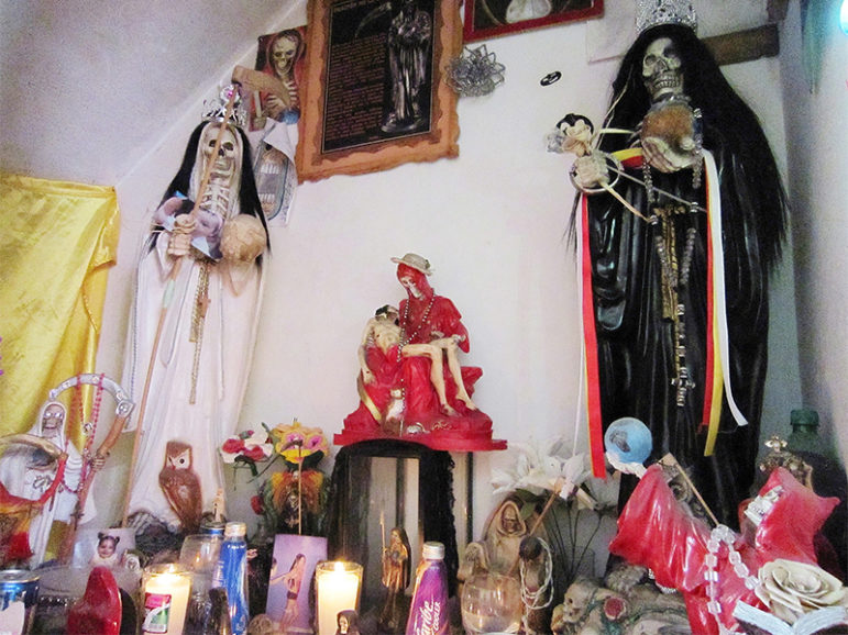 A shrine to Santa Muerte kept in the house of Betzy Ballesteros in Guadalajara, Mexico. The shrine includes statues, candles, candy and photos of several of Ballesteros’ transgender friends who were murdered and abandoned. RNS photo by Stephen Woodman
