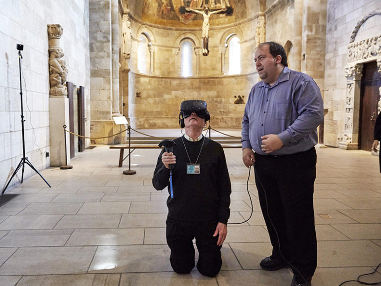 The Rev. Xavier Seubert, left, of the Friary of St. Francis of Assisi in Manhattan explores the interior of an intricately carved prayer bead using a VR headset, guided by Joseph Ellsworth of the Canadian Film Center, on April 3, 2017. The exhibit 