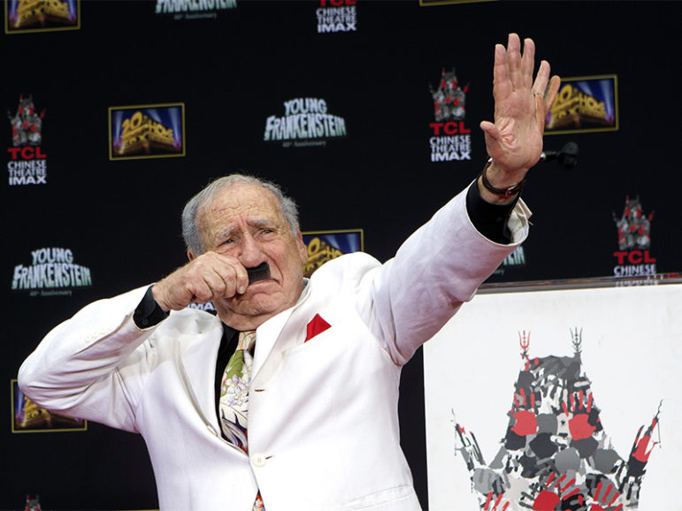 Filmmaker and comedian Mel Brooks uses a comb to mimic a Hitler mustache as he places his footprints in cement, with a fake sixth finger attached to his left hand, in the forecourt of the TCL Chinese theatre in Hollywood, Calif., on  Sept. 8, 2014. Photo courtesy of Reuters/Mario Anzuoni