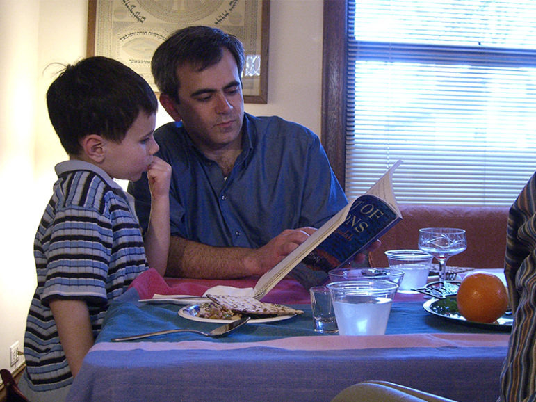 A man helps a young boy with the Four Questions during a 2006 Passover seder. Photo courtesy of Creative Commons/Sandor Weisz