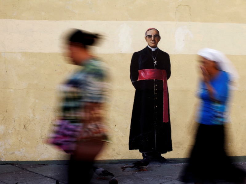 People walk by a graffiti of the murder of late Archbishop of San Salvador Oscar Arnulfo Romero on May 18, 2017, in San Salvador, El Salvador. Photo by Jose Cabezas/REUTERS