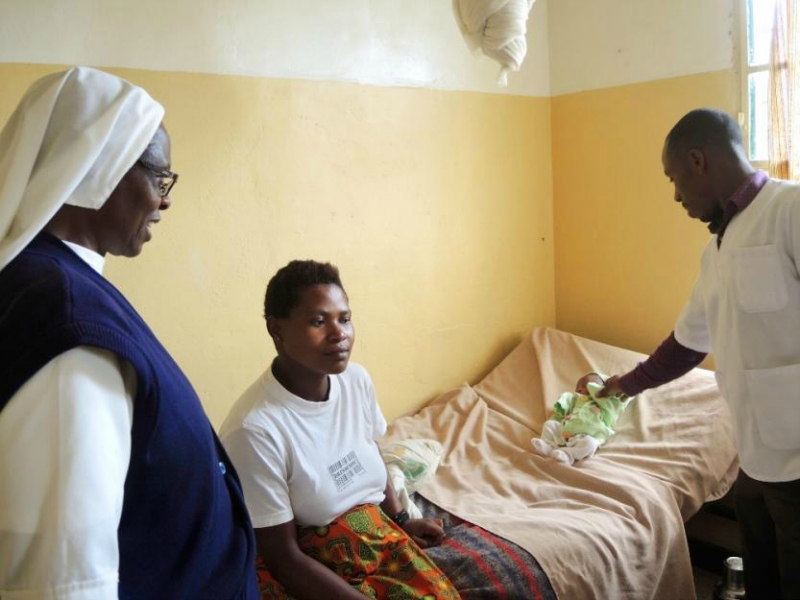 Sr. Margaret Wanjiku Njunguna, left, and a nurse check up on a newborn baby with a cold at the health center in Muyanza, Rwanda. 