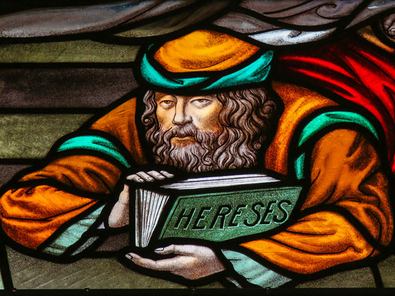 Stained glass window depicting a heretic in the Cathedral of Saint Rumbold in Mechelen, Belgium. Heretic image courtesy www.shutterstock.com