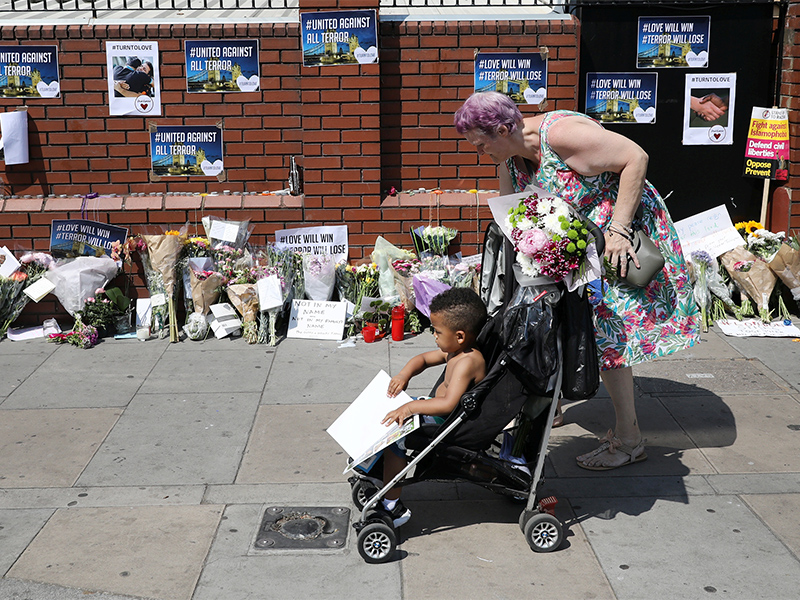 A woman arrives with flowers to lay with other tributes at the base of a wall near the scene of an attack next to Finsbury Park Mosque, in north London, Britain, on June 20, 2017. Photo courtesy of Reuters/Marko Djurica