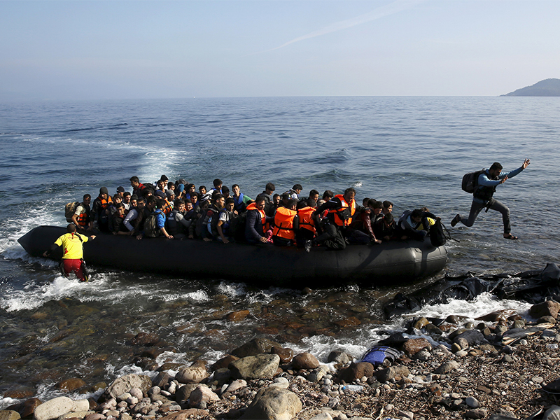 An Afghan migrant jumps off an overcrowded raft onto a beach at the Greek island of Lesbos on Oct. 19, 2015. Thousands of refugees — mostly fleeing war-torn Syria, Afghanistan and Iraq — attempt daily to cross the Aegean Sea from nearby Turkey, a short trip but a perilous one in the inflatable boats the migrants use, often in rough seas. Photo by Yannis Behrakis/Reuters