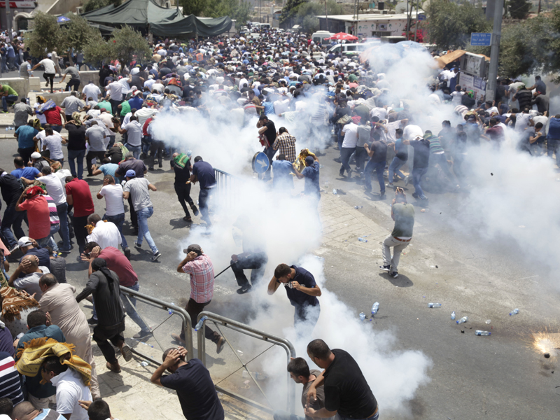 Palestinians run away from tear gas thrown by Israeli police officers outside Jerusalem's Old City on July 21, 2017. Israel police severely restricted Muslim access to a contested shrine in Jerusalem's Old City that day to prevent protests over the installation of metal detectors at the holy site. (AP Photo/Mahmoud Illean)