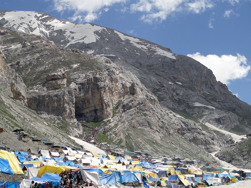 Tents are seen at the base of the imposing Amarnath Cave, which Hindu pilgrims walk to in the background.  Photo courtesy of Creative Commons/Hardik Buddhabhatti