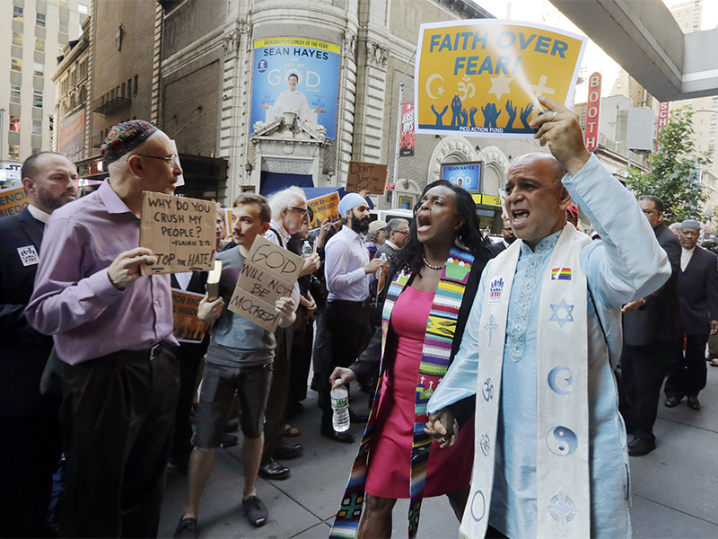 Clergy leaders with PICO Action Fund and their local federation, Faith in New York, demonstrate outside the hotel in New York's Times Square, on June 21, 2016, where Republican presidential candidate Donald Trump is scheduled to meet evangelical clergy. (AP Photo/Richard Drew)
