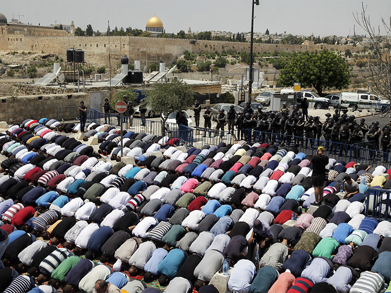 Palestinians pray outside Jerusalem's Old City on July 21, 2017. Israel police, right, severely restricted Muslim access to the Temple Mount in Jerusalem's Old City on Friday to prevent protests over the installation of metal detectors at the holy site. (AP Photo/Mahmoud Illean)