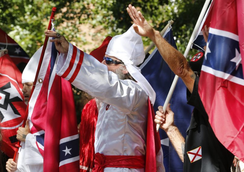 Klan members salute during a KKK rally in Justice Park Saturday, July 8, 2017, in Charlottesville, Va. (AP Photo/Steve Helber)