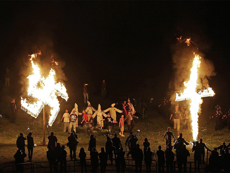 Members of the Ku Klux Klan participate in cross and swastika burnings after a 