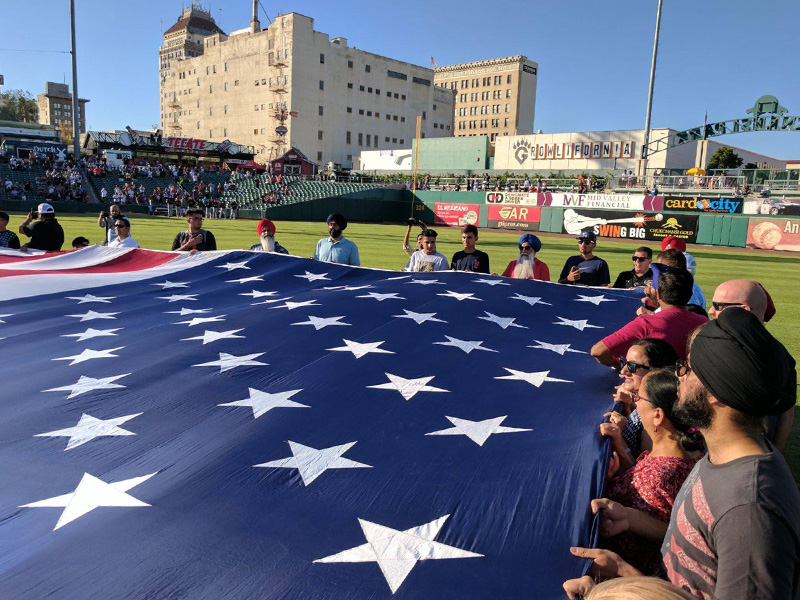 We Are Sikhs representatives hold the American flag at a Fresno Grizzlies baseball game in Fresno, Calif., on July 4, 2017.  Photo by Christina Hulick