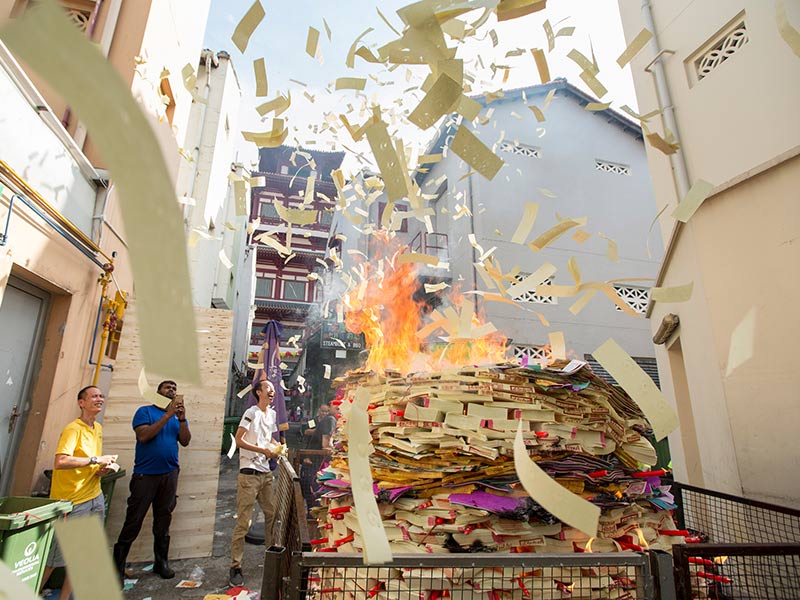 A team from a local company burns paper offerings on a back alley in Singapore's China Town during the Hungry Ghost Festival. They consider their paper offering as being the biggest in the neighborhood, with a value of more than 1000 SGD. Companies often make paper offerings during the festival to seek prosperity and luck in the future. RNS photo by Alexandra Radu