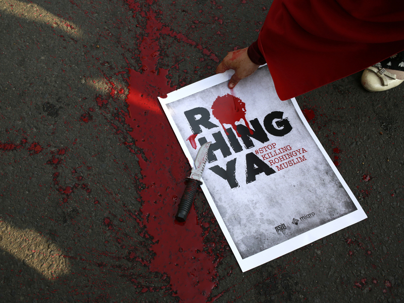 A Muslim protester picks up a poster as fake blood is seen spattered on the ground after a theatrical act depicting the violence against Muslim Rohingya in western Myanmar performed during a rally on Sunday, Sept. 3, 2017 in Jakarta, Indonesia. The violence erupted on Aug. 25, when insurgents from the Rohingya ethnic minority attacked Myanmar police and paramilitary posts in what they said was an effort to protect minority Rohingya. In response, the military unleashed what it called 