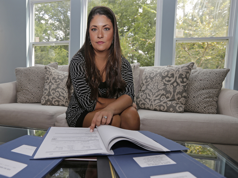 Former Word of Faith Fellowship church member Rachael Bryant poses for a photo with her tax records at her home in Charlotte, N.C., on Sept. 19, 2017. She and 10 other members of the evangelical North Carolina-based church say their leader, Jane Whaley, coerced congregants into filing false unemployment claims after the faltering economy threatened weekly tithes from church-affiliated companies. (AP Photo/Chuck Burton)