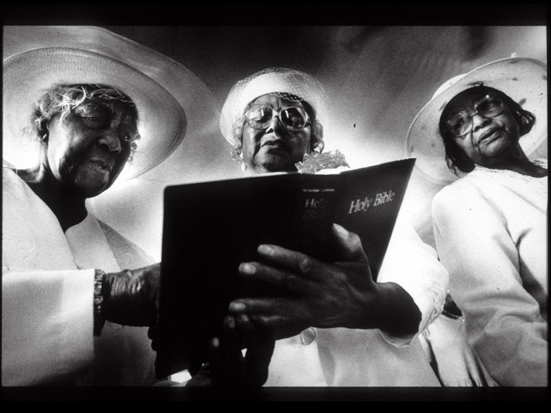 Three women read from the Bible during church services. Photograph by Brian Walski