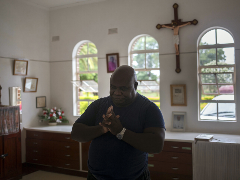 Fidelis Mukonori, a Catholic priest who mediated talks with Zimbabwe's former President Robert Mugabe, prays inside the sacristy after mass in Chishawasha, Sunday, Nov. 26, 2017.  Mugabe knew it was 