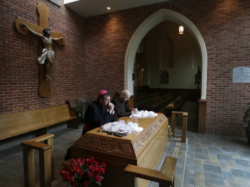 In this May 4, 2017, file photo, Archbishop Allen Vigneron, left, and Michael Sullivan, provincial minister of the Capuchin Franciscan Province of St. Joseph, pray at the tomb of Father Solanus Casey in Detroit. The Detroit priest, who is credited with helping cure a woman with a skin disease, is being beatified by the Roman Catholic Church, a major step toward sainthood, Nov. 18 in Detroit. (AP Photo/Carlos Osorio)