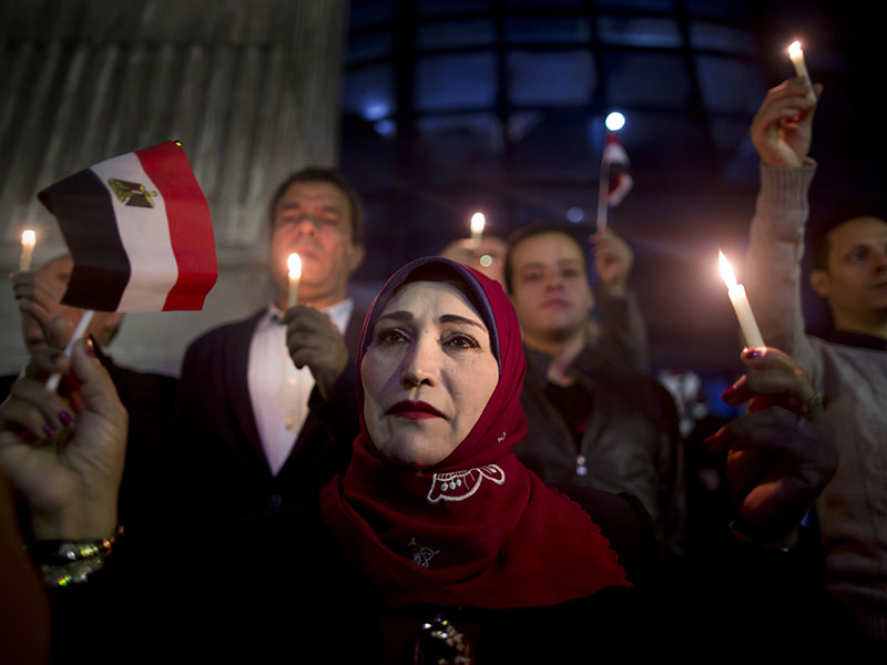 People take part during a candlelight vigil as they hold national flag for victims of a Friday mosque attack at the Journalists Syndicate, in Cairo, Egypt, Monday, Nov. 27, 2017. Friday's assault was Egypt's deadliest attack by Islamic extremists in the country's modern history, a grim milestone in a long-running fight against an insurgency led by a local affiliate of the Islamic State group.(AP Photo/Amr Nabil)