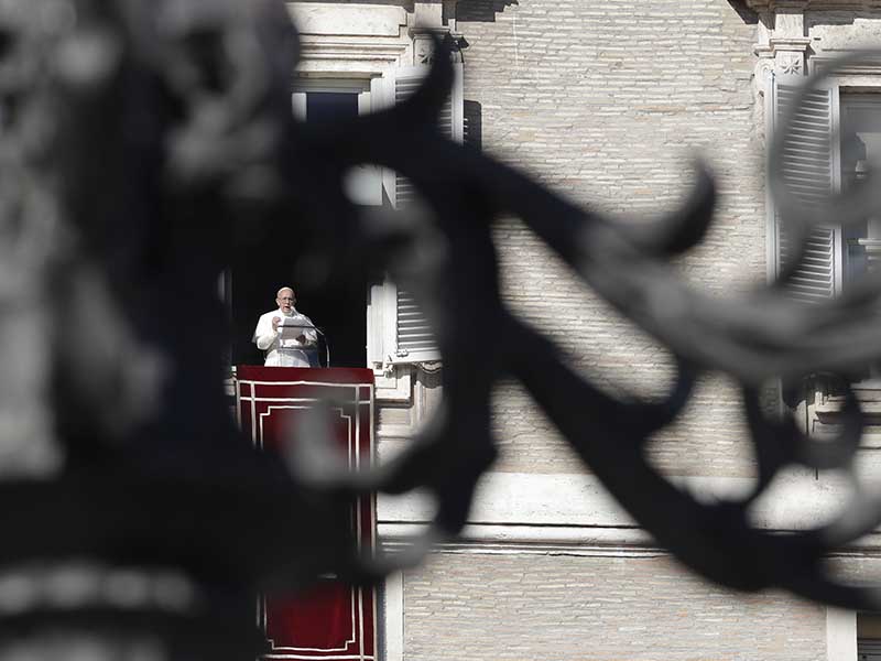 Pope Francis is framed by the decoration of a street lamp as he recites the Angelus prayer at the window of his studio overlooking St. Peter's Square at the Vatican on Nov. 19, 2017. (AP Photo/Andrew Medichini)