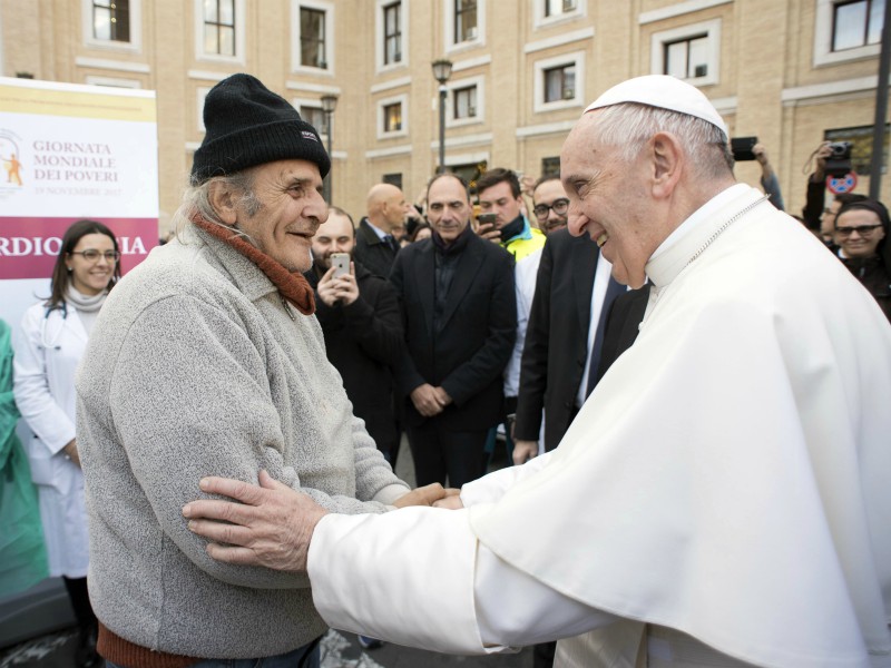 Pope Francis greets an unidentified man during a surprise visit to a small facility near St. Peter's Square where doctors on a volunteer basis give poor people medical exams, at the Vatican, Nov. 17, 2017. Francis on Thursday decried that, increasingly, only the privileged can afford sophisticated medical treatments, and he urged lawmakers to ensure that health care laws protect the “common good.” (L'Osservatore Romano/Pool Photo via AP)