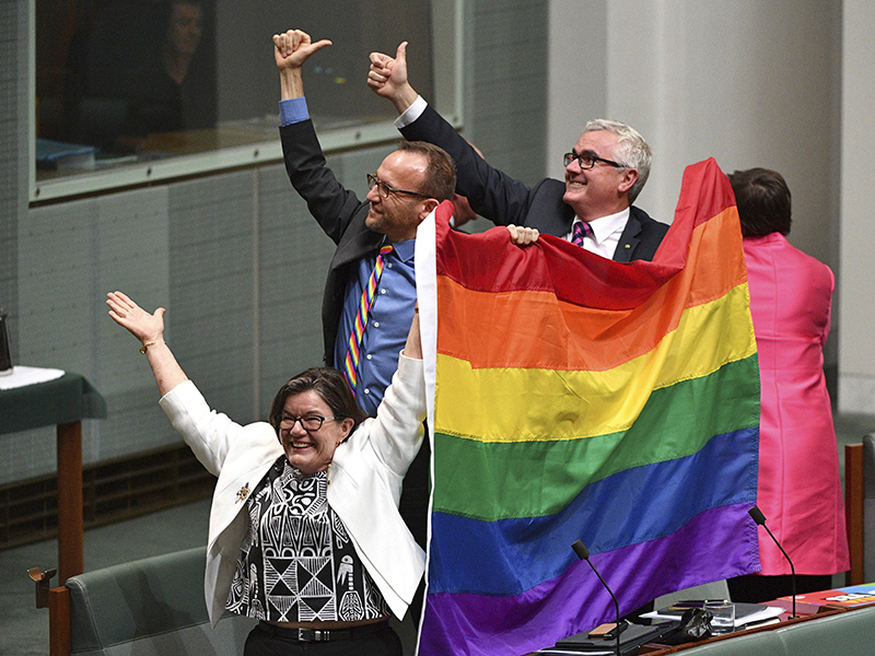 Members of parliament, from left, Cathy McGowan, Adam Brandt and Andrew Wilkie celebrate the passing of the Marriage Amendment Bill in the House of Representatives at Parliament House in Canberra, Thursday, Dec. 7, 2017. Gay marriage was endorsed by 62 percent of Australian voters who responded to a government-commissioned postal ballot by last month. (Mick Tsikas/AAP Image via AP)