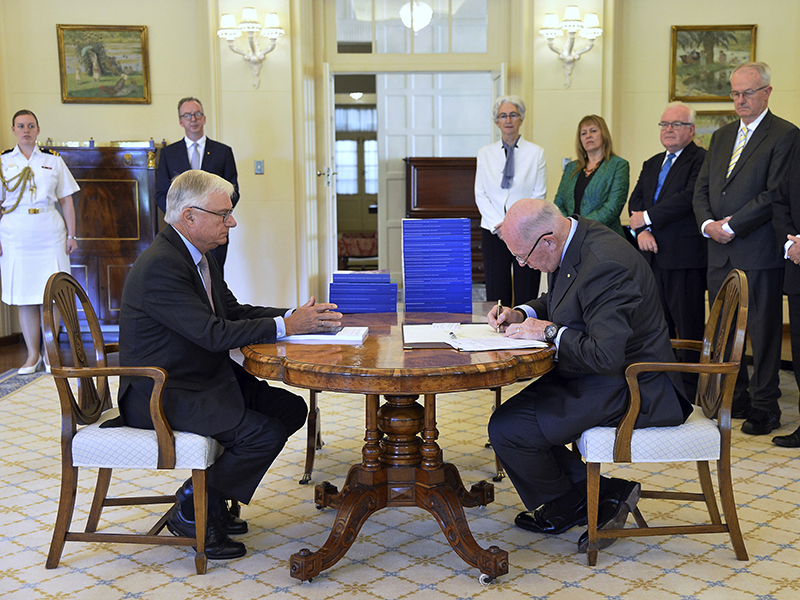 In this photo provided by the Australian Government Royal Commission, Commissioner Justice Peter McClellan, seated left, watches as Governor-General of Australia Peter Cosgrove, seated right, signs a document after receiving the final report of the Royal Commission into Institutional Responses to Child Sexual Abuse at Government House, in Canberra, Dec. 15, 2017. The commission delivered its final 17-volume report and 189 recommendations after a wide-ranging investigation. (Jeremy Piper/Australian Government Royal Commission via AP) (Caption amended by RNS)