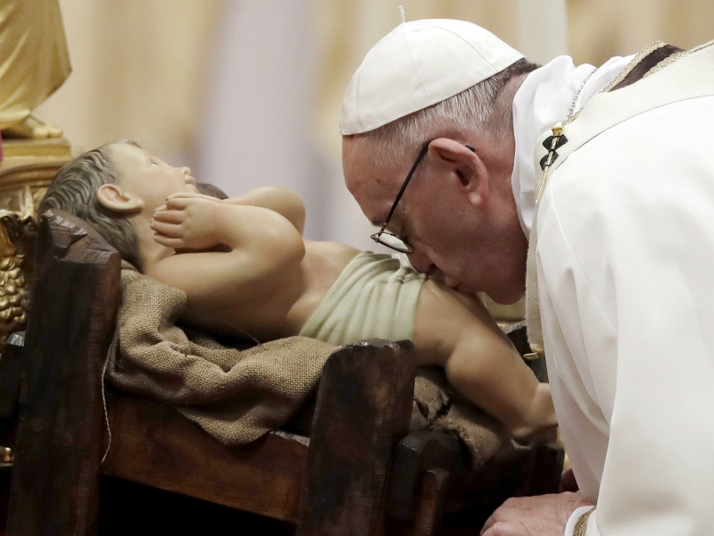 Pope Francis kisses a statue of Baby Jesus as he celebrates the Christmas Eve Mass in St. Peter's Basilica at the Vatican, Sunday, Dec. 24, 2017. (AP Photo/Alessandra Tarantino)